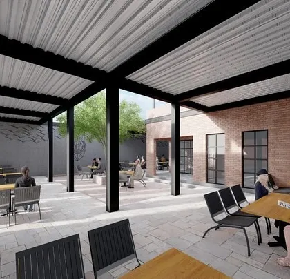 This view from under the covered patio shows the relationship between the indoor and outdoor spaces. The use of exposed brick walls and large window frames helps connect the different areas of the cafe seamlessly.