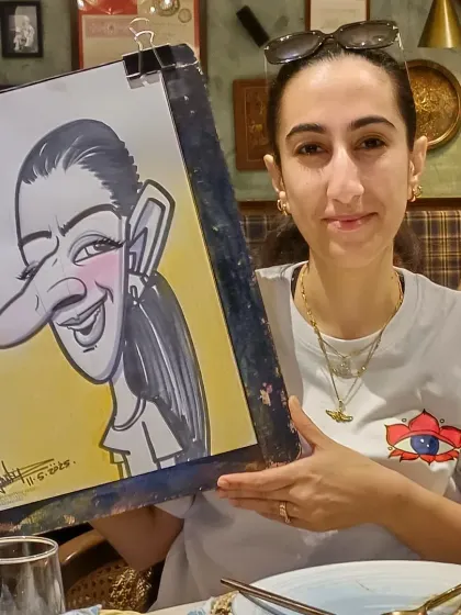 A guest at Mr. Merchant with her finished drawing. The simple yellow background makes the portrait stand out.
