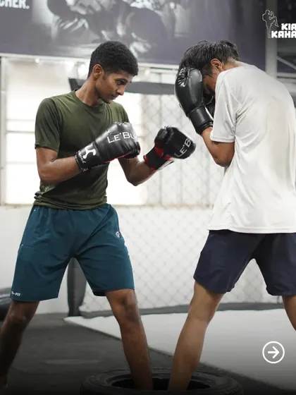 Two students practice their boxing footwork and defense, circling each other inside tires to improve agility and close-quarters movement.