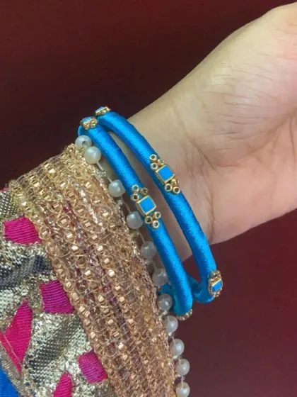 A simple pair of blue silk thread bangles with delicate pearl and kundan accents.