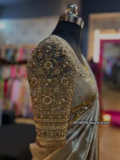 A close-up of the sleeve, covered in dense, intricate gold embroidery.