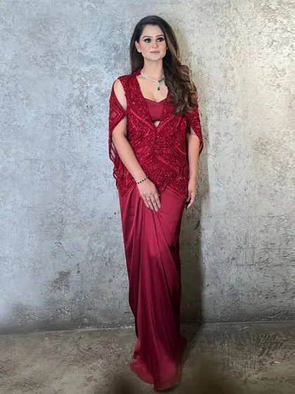 A client wearing an enchanting red cape paired with a draped bottom, a stunning ensemble that redefines festive elegance.