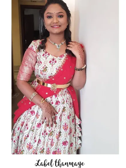 A client looking radiant in a Kalamkari silk lehenga with a red dupatta and a gold waist belt.