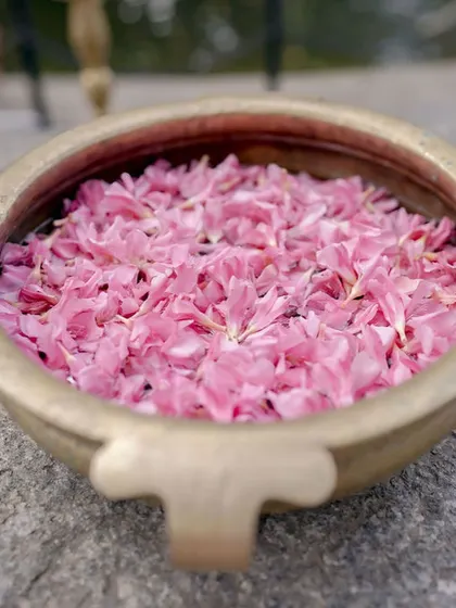 A brass urli filled with pink flower petals, a simple yet beautiful decor detail.