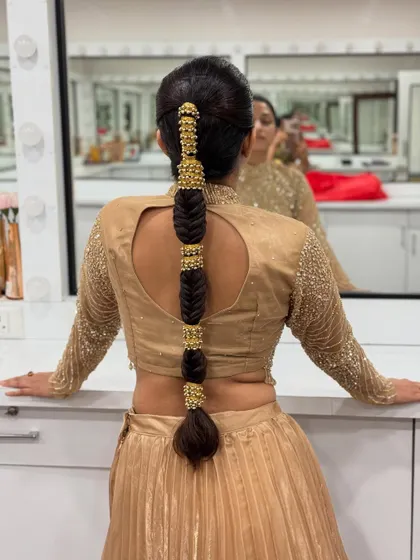 The model leaning against the mirror shows off the clean lines and modern appeal of this segmented bubble braid. It's a chic and stylish choice for any event.