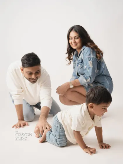 A playful family moment on the studio floor, with everyone on all fours, crawling and laughing together.