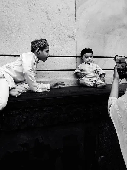 A candid black and white moment in Jama Masjid, where a mother takes a photo of her two young sons. It's a universal story of family and memory set within a historic location.