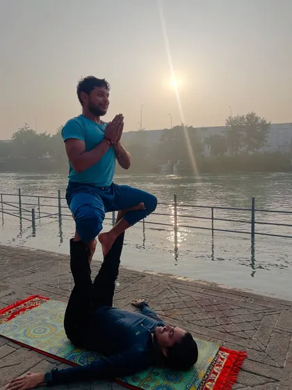 The 'throne' pose in acroyoga, where the flyer sits gracefully on the base's feet, framed by the rising sun.