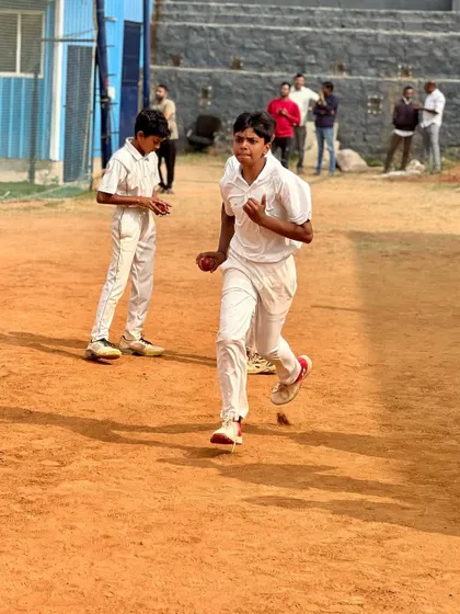 A young cricketer completes his bowling follow-through on the clay surface. This image captures the dynamic movement and energy of our outdoor training.