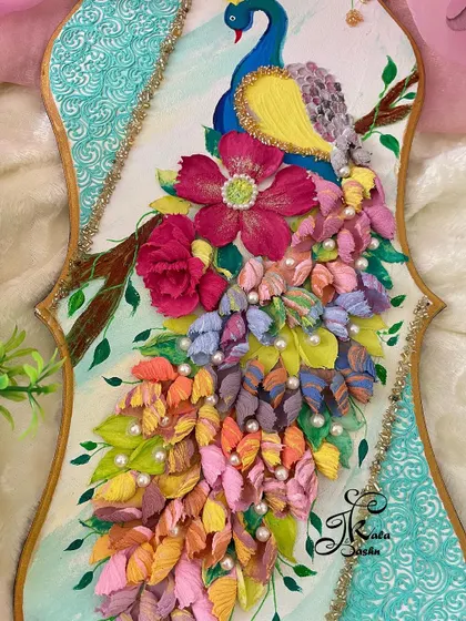 An angled view of another peacock piece, this one featuring a more floral-heavy design with large pink flowers and pearl accents.