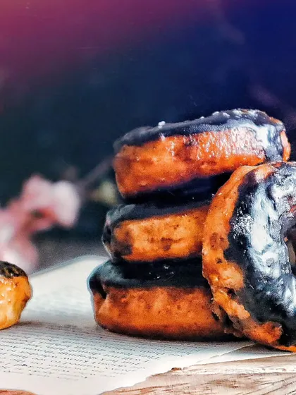 Another view of the stacked chocolate donuts, with a hint of floral elements in the background. This adds a touch of softness to the otherwise dark and moody shot.