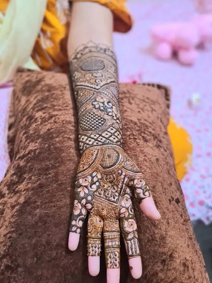 A single-arm view of a complex bridal design, featuring a mix of florals, paisleys, and geometric fillers.