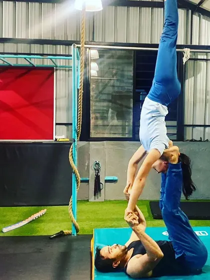 I often act as the base for my students in acro yoga. These images showcase various poses like 'bird' and 'throne', which are great for developing balance and core strength for the flyer.