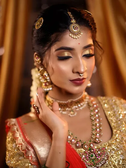 A beautiful pose capturing the shimmer of the golden eye makeup and the intricate details of the temple jewellery. The skin has a flawless, airbrushed finish.