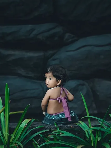 A beautiful little mermaid looking back over her shoulder. The dark, rocky background makes her tail stand out.