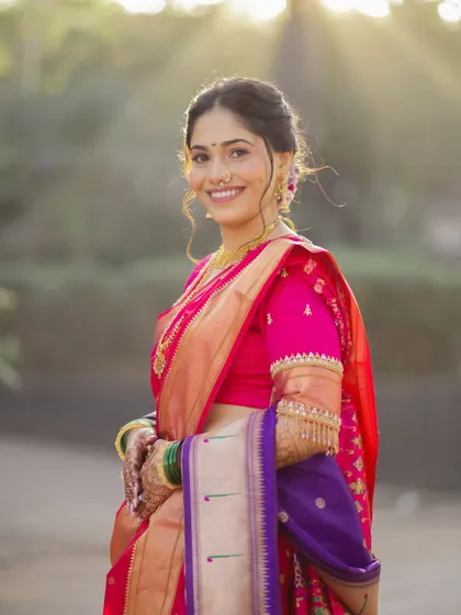 A radiant bride ready for her wedding. This portrait captures the complete look, from the elegant hairstyle and makeup to the beautiful pink and purple Nauvari saree.