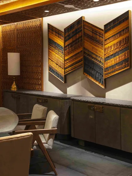 The dining room features a striking folded artwork that adds a contemporary, sculptural element to the wall. The custom sideboards provide storage while maintaining the room's sleek aesthetic.