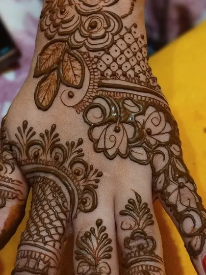 A close-up of a beautiful Arabic-style floral pattern on the back of the hand. The combination of leaves, flowers, and net patterns is very elegant.