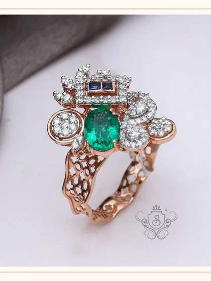 An avant-garde design for the bold and fashionable. This custom ring features a central oval green gemstone, surrounded by an abstract arrangement of diamonds and sapphires on a textured rose gold band.