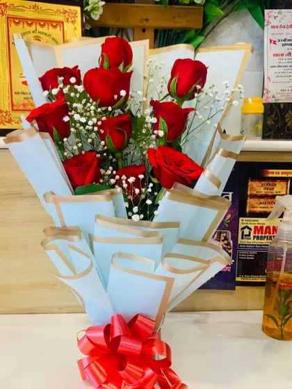 A simple bouquet of red roses and baby's breath wrapped in light blue paper. This is a great example of a classic, affordable, and beautiful floral gift.
