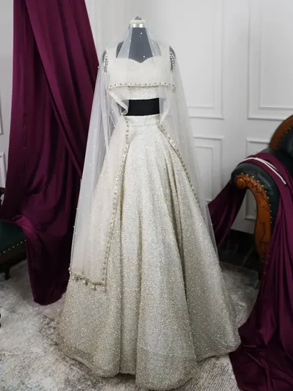 The full ivory lehenga set on a mannequin, complete with the sheer veil. This presentation highlights the complete bridal vision, showing how each element works together to create a look of pure elegance.