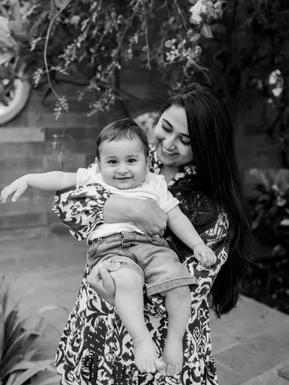 A mother and her happy baby boy, captured in a classic black and white outdoor portrait. His joyful expression is the absolute center of this photograph.