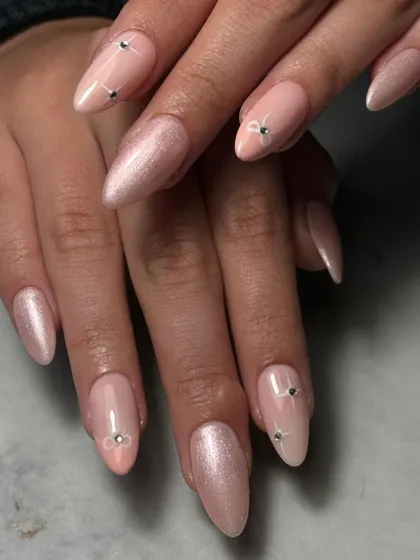 Understated elegance. This set features a sheer, shimmery nude base on almond-shaped nails, accented with tiny, perfectly placed floral-shaped gems.