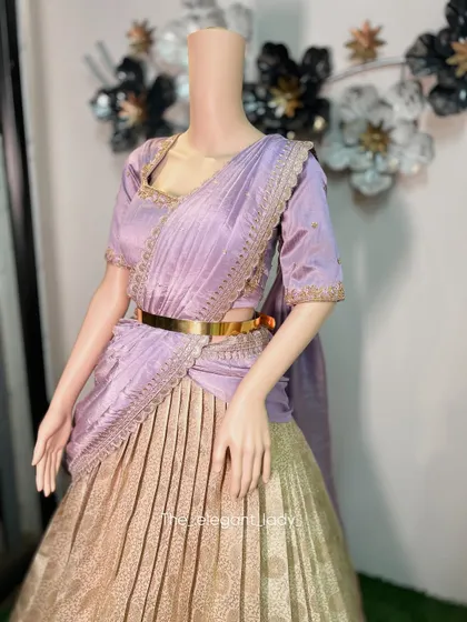 A close-up of a beautiful lavender and gold half-saree. The delicate embroidery on the blouse and the shimmering fabric of the skirt create a look of soft elegance, perfect for an engagement or reception.