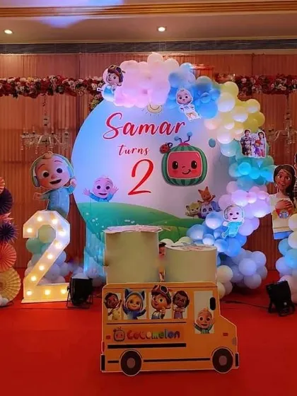A Cocomelon theme for a 2nd birthday, featuring a character backdrop, a Cocomelon school bus prop, and a marquee number '2'. The setup is perfect for a stage or photo corner.