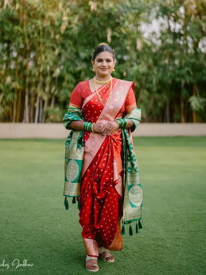 A full-length portrait of the bride, Ankita, in a traditional red Nauvari saree, looking poised and elegant.