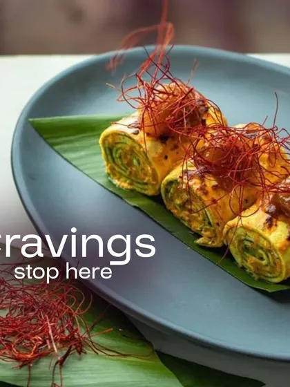 Cravings stop here. These delicate rolls, garnished with fine chili threads, are plated on a banana leaf, showcasing a fusion of Asian flavors and modern presentation.
