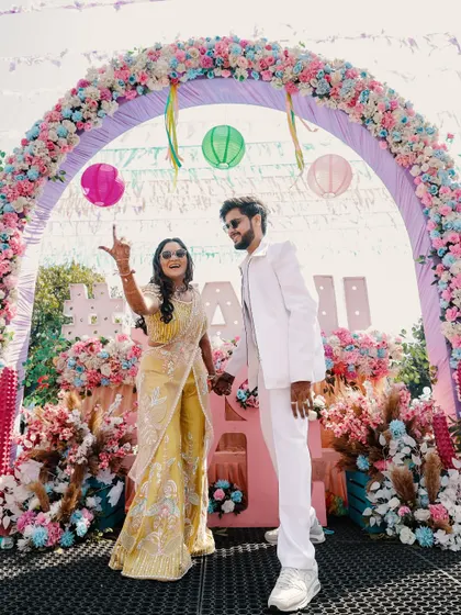 The couple makes a grand entrance under a stunning floral arch at their Haldi and pool party. A perfect start to a day filled with celebration.