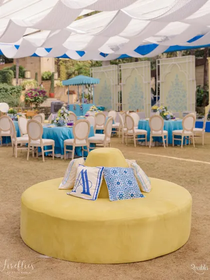 A central yellow ottoman with custom monogrammed cushions in the signature blue and white of the Jodhpur-themed Haldi. This piece served as a stylish and comfortable focal point in the lounge area.