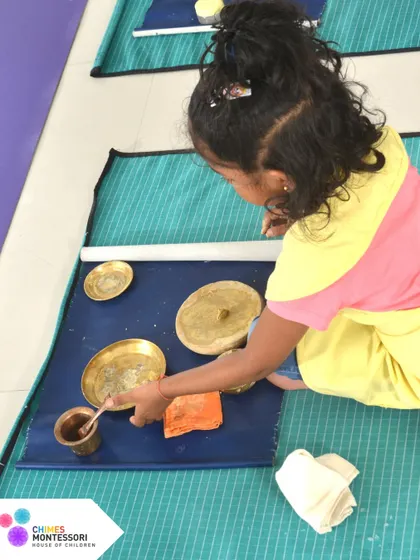 A child polishes brass utensils, a practical life skill that also teaches care for the environment and a sense of order.