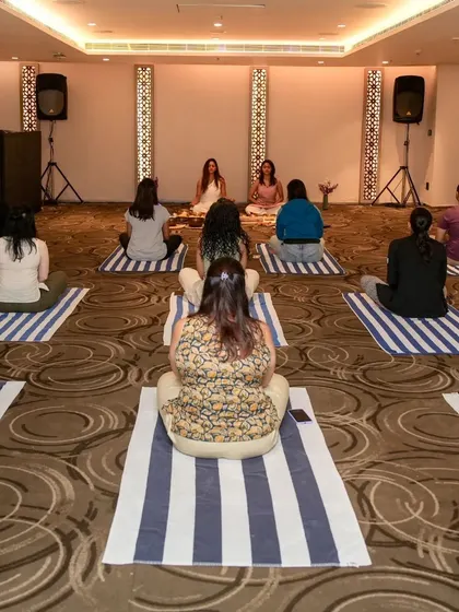 A wide view of a sound healing session in a hotel ballroom, showing participants spaced out for a comfortable and immersive experience.