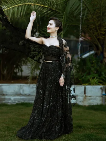 The full look of the black sequined lehenga set, complete with a delicate lace cape for added drama.