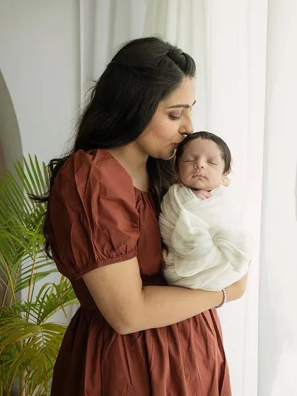 A mother's tender kiss on her newborn's forehead. This vertical portrait is a beautiful, emotional close-up of the maternal bond.