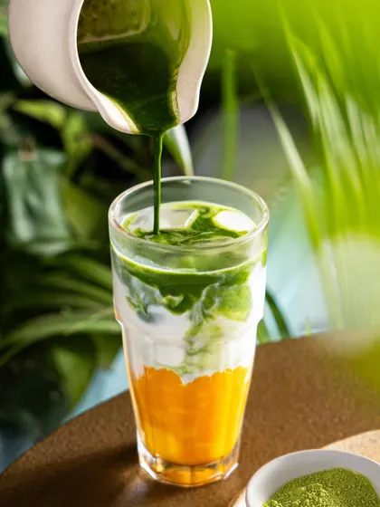 A three-layered drink from Mokai with mango, milk, and matcha. This shot highlights the beautiful separation of colors and the artistry of the drink's construction.