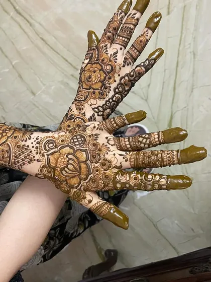 Both hands together, displaying the front and back Arabic floral designs.
