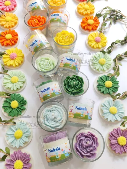 A closer view of the colorful birthday return gifts, showing the personalized "Naksh" stickers on the votive candles.