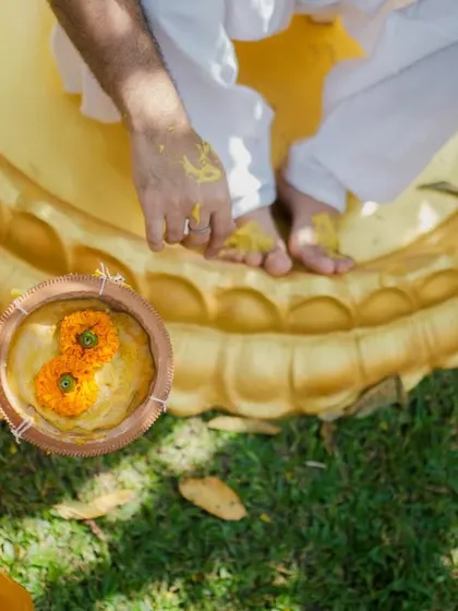 A detail shot of a bowl of haldi paste and marigold flowers, capturing the elements of the ceremony before the fun begins.