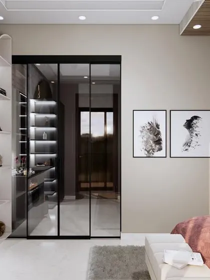This angle shows the seamless integration of the walk-in closet, which is separated by sleek, black-framed glass doors. The design maintains an open feel while providing distinct functional zones.