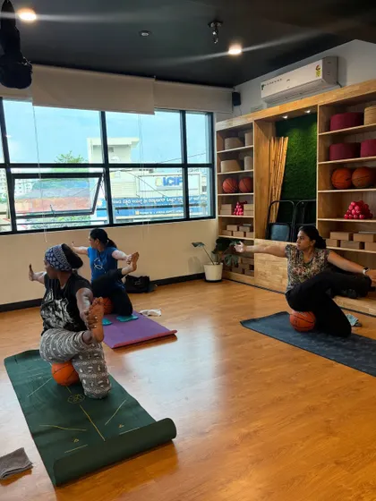 Students practice a seated twist on basketballs, a creative way to challenge balance and engage the core.