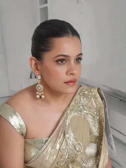 A side profile of Kirti's look, highlighting her sleek bun and glowing skin.