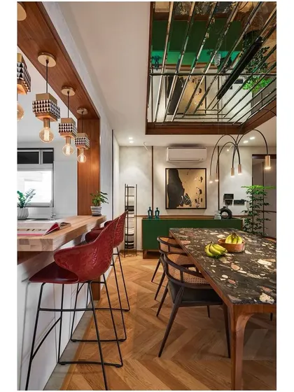 The breakfast bar and dining area flow together, united by the herringbone wooden flooring and a consistent language of contemporary design.