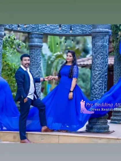 A couple posing near stone pillars, with the woman in a royal blue trail gown. The man's dark suit complements the deep blue of the dress perfectly.