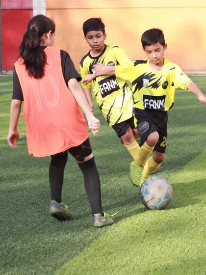A female player in a bib challenges for the ball in a mixed-gender practice match. This inclusive environment helps all players develop their skills.