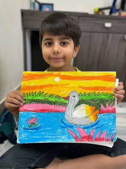 A first-grade student shows off his beautiful drawing of a duck swimming in a pond at sunset. In my drawing classes for kids, we focus on basic shapes and colour blending to create charming animal art.