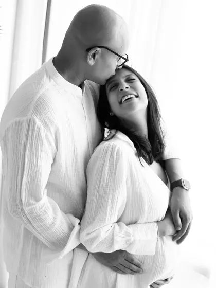 The beauty of a candid laugh. This black and white photo perfectly freezes a moment of pure happiness and connection between the expecting parents.