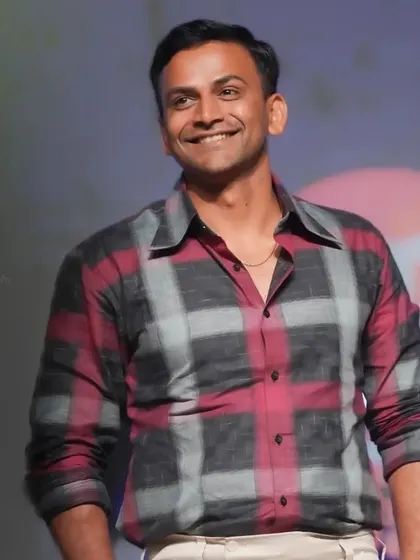 A smiling portrait of actor Dhananjaya on stage. This photo captures his charismatic presence during an event.